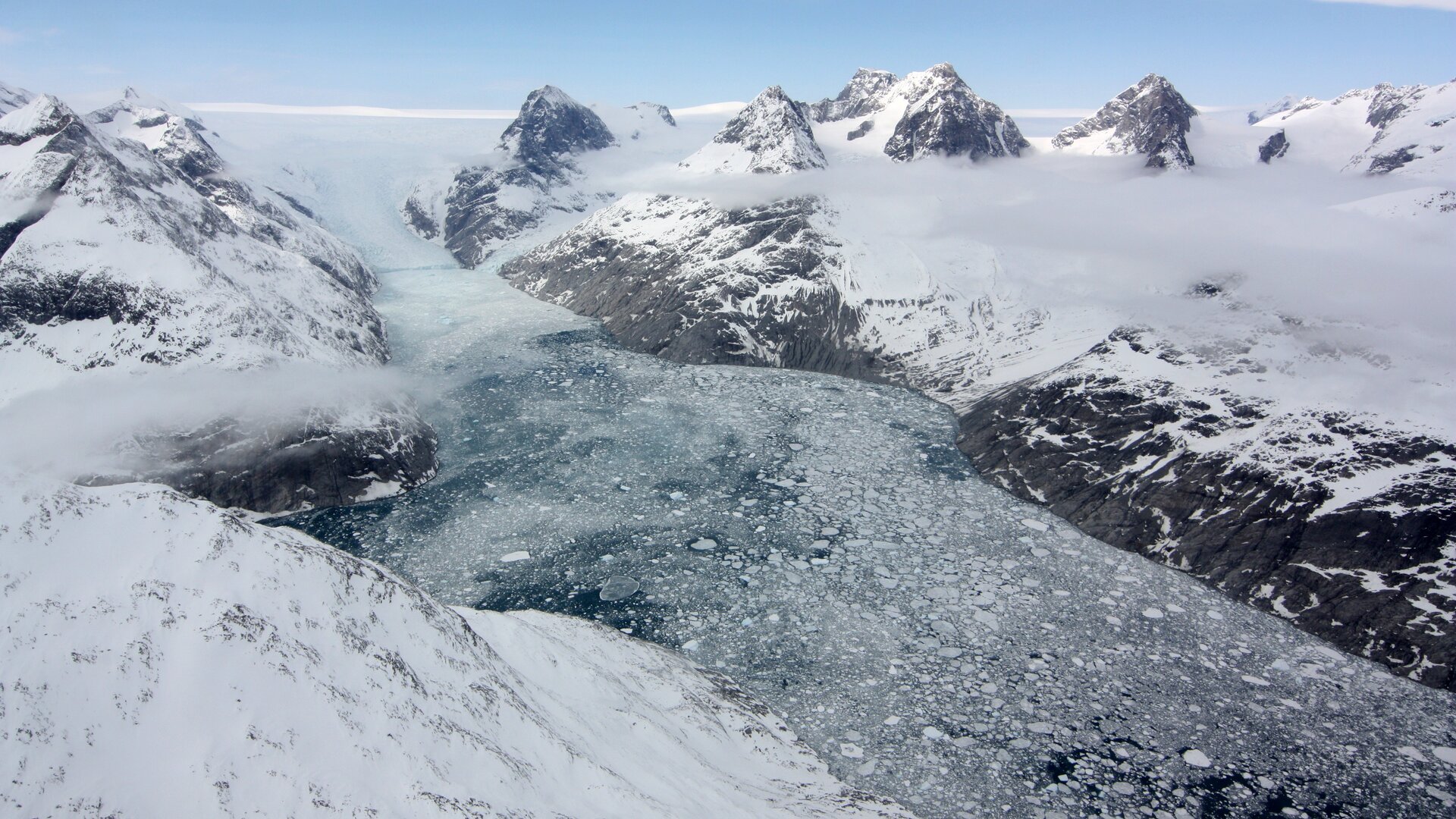 Optical imagery acquired during a NASA Operation IceBridge (OIB) flight at a glacier in the Southern Greenland, where a fjord with a marine-terminating glacier is observed as well as the ice tounge, icebergs, and sea ice of the mélange. 